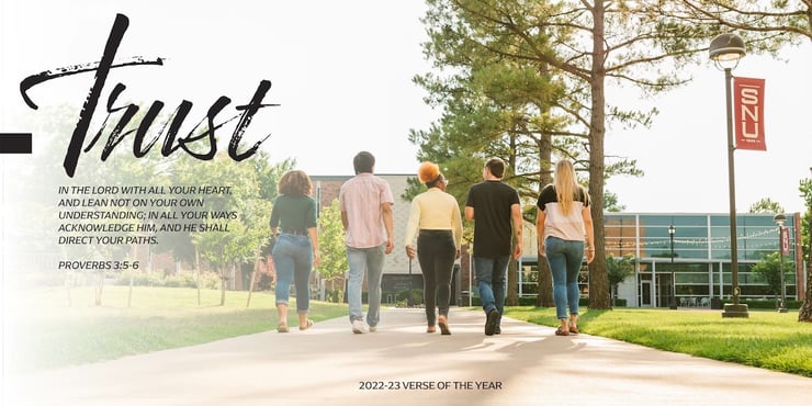 A group of five students walking through the quad of the Southern Nazarene University campus. The image has a text overlay that reads: “Trust in the Lord with all your heart and lean not on your own understanding; in all your ways acknowledge him, and he shall direct your paths. — Proverbs 3:5-6, 2022-23 Verse of the Year” 