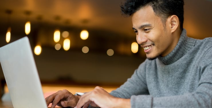 Person smiling on their computer looking for a job after completing their degree with SNU's professional and graduate studies program
