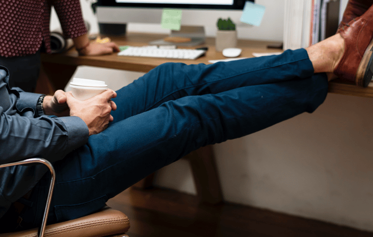 person leaning in chair with feet on desktop