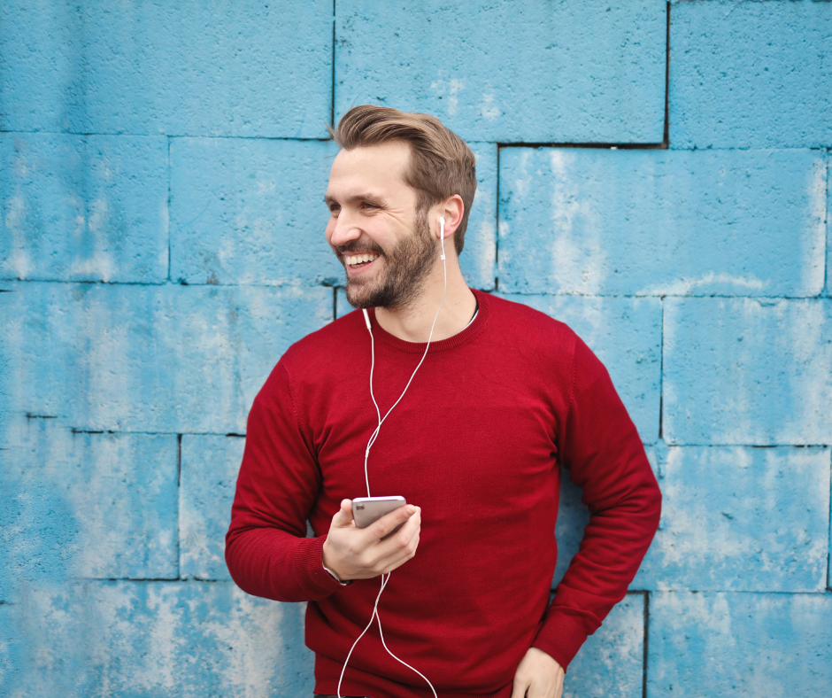 person smiling, standing against blue wall