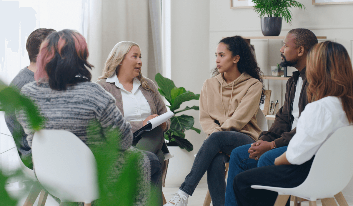 Adults sitting in a circle speaking to a mental health conselor